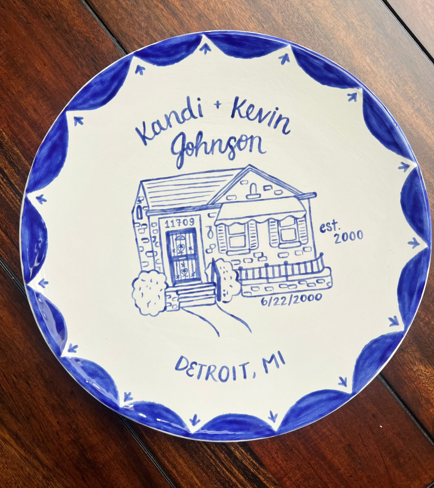 Decorative ceramic plate with a house illustration and text on a wooden surface