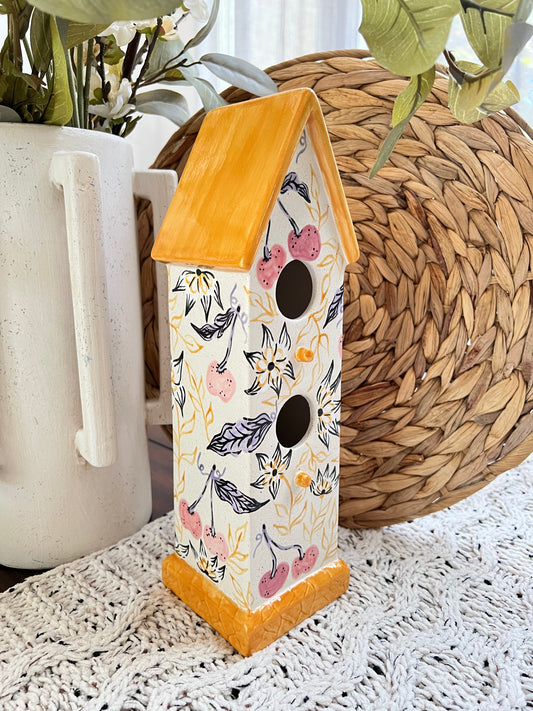 Decorative birdhouse with floral pattern on a textured surface