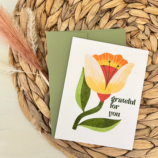 Greeting card with floral design and 'Grateful for you' text on a woven mat.