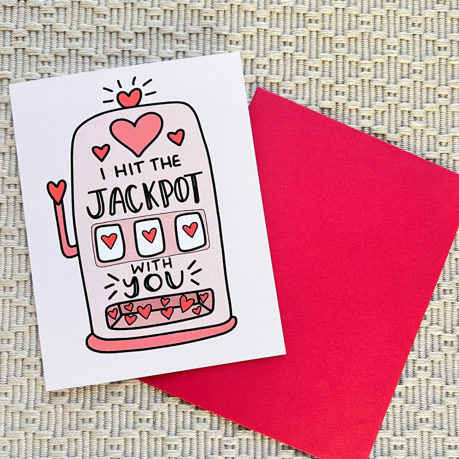 Greeting card with 'I hit the jackpot with you' design and a red envelope on a textured surface