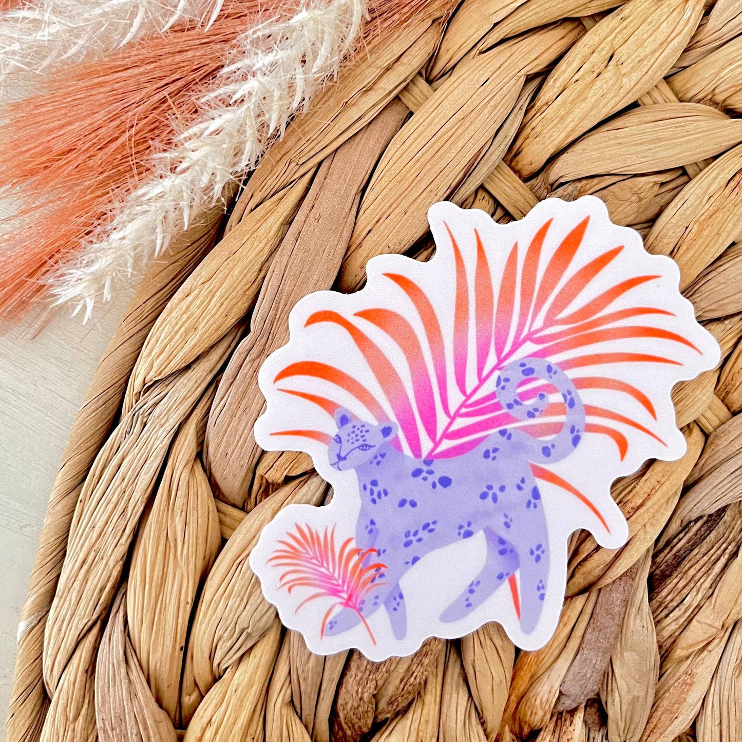 Colorful leopard illustration sticker on a woven mat with dried plants