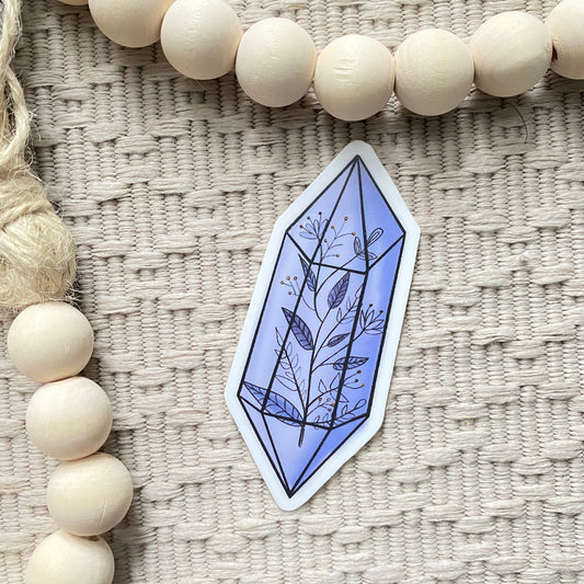 Geometric amethyst crystal design sticker on a textured surface with wooden beads