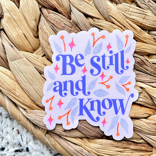 Sticker with 'Be still and know' text on a woven mat background