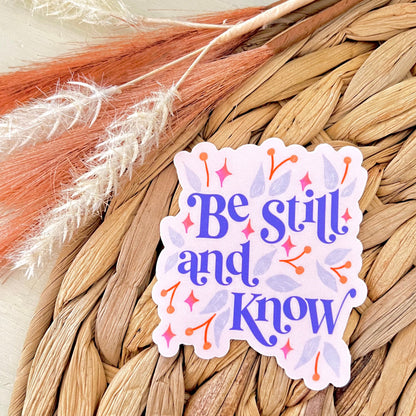 Sticker with 'Be still and know' text on a woven mat background