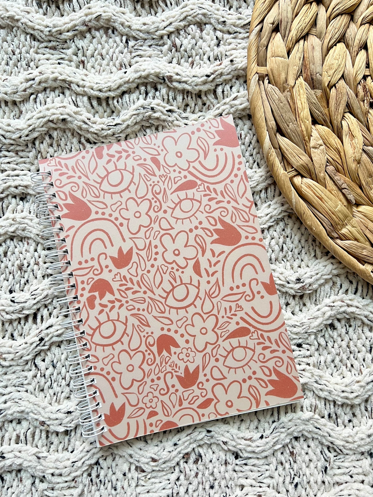Beige patterned notebook on a textured surface with a woven mat