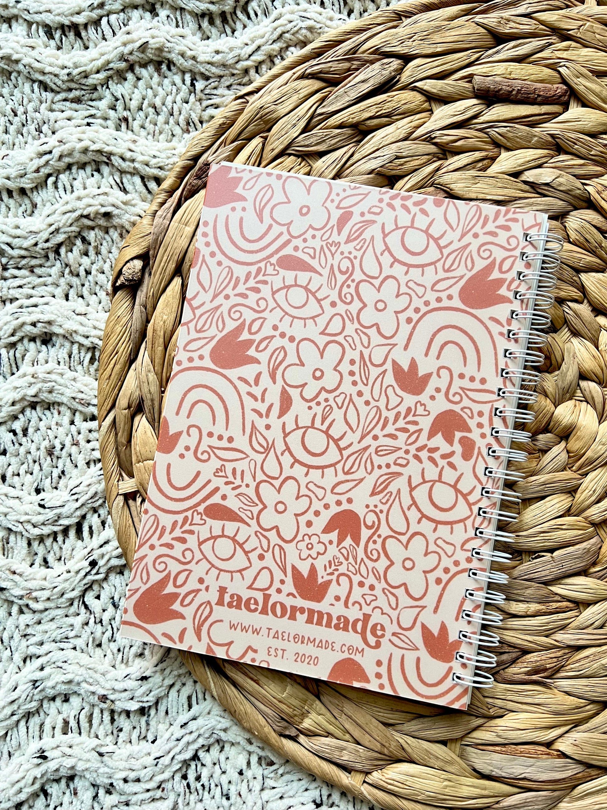 Notebook with a orange floral pattern on a woven mat