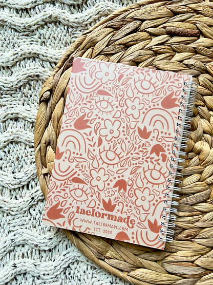 Notebook with a orange floral pattern on a woven mat