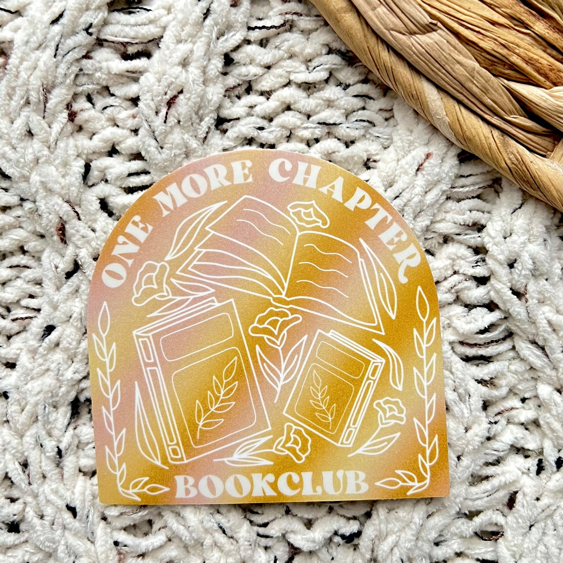 Decorative sticker with 'One More Chapter Bookclub' text on a textured surface