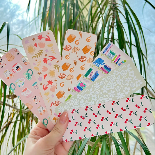 Hand holding a set of colorful patterned bookmarks with a natural background