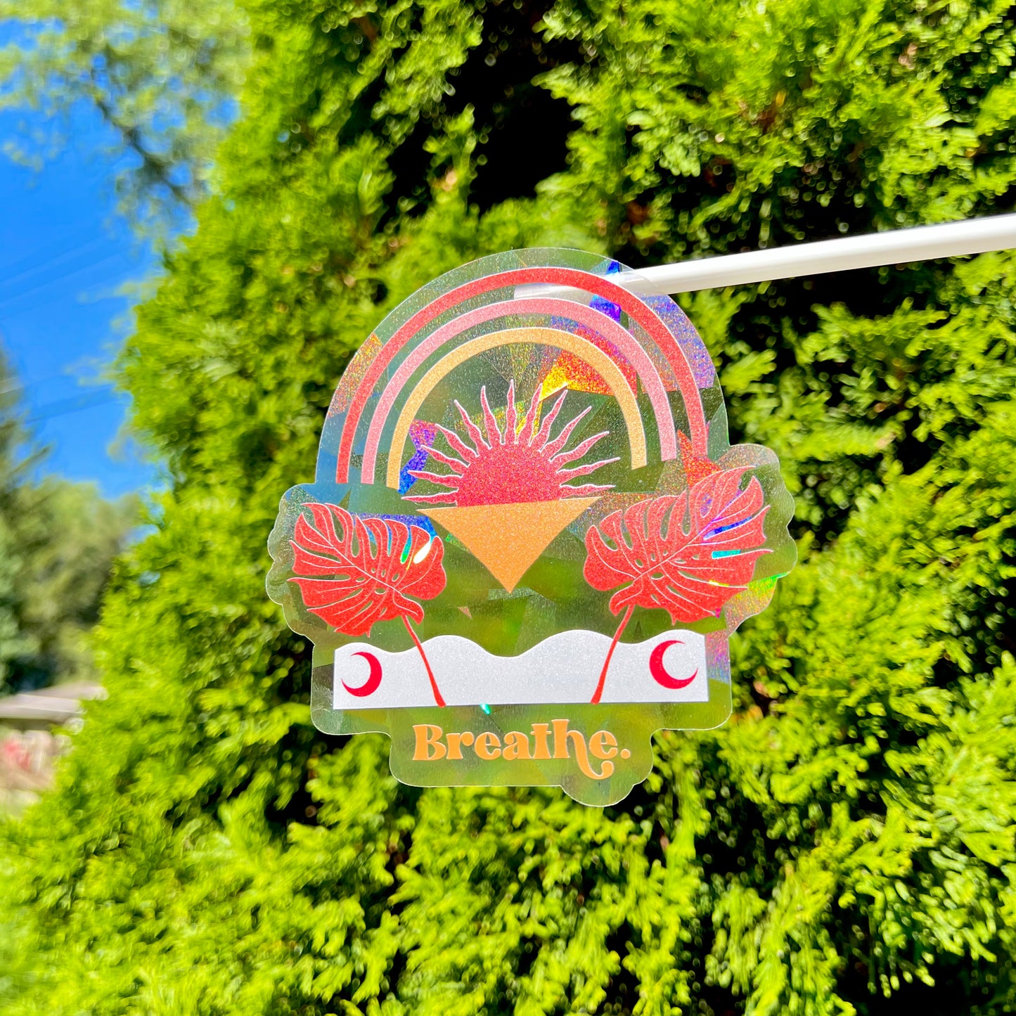 Decorative sticker with plants and 'Breathe' text against a green foliage background