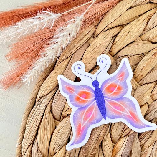 Butterfly-shaped sticker with gradient colors on a woven mat background