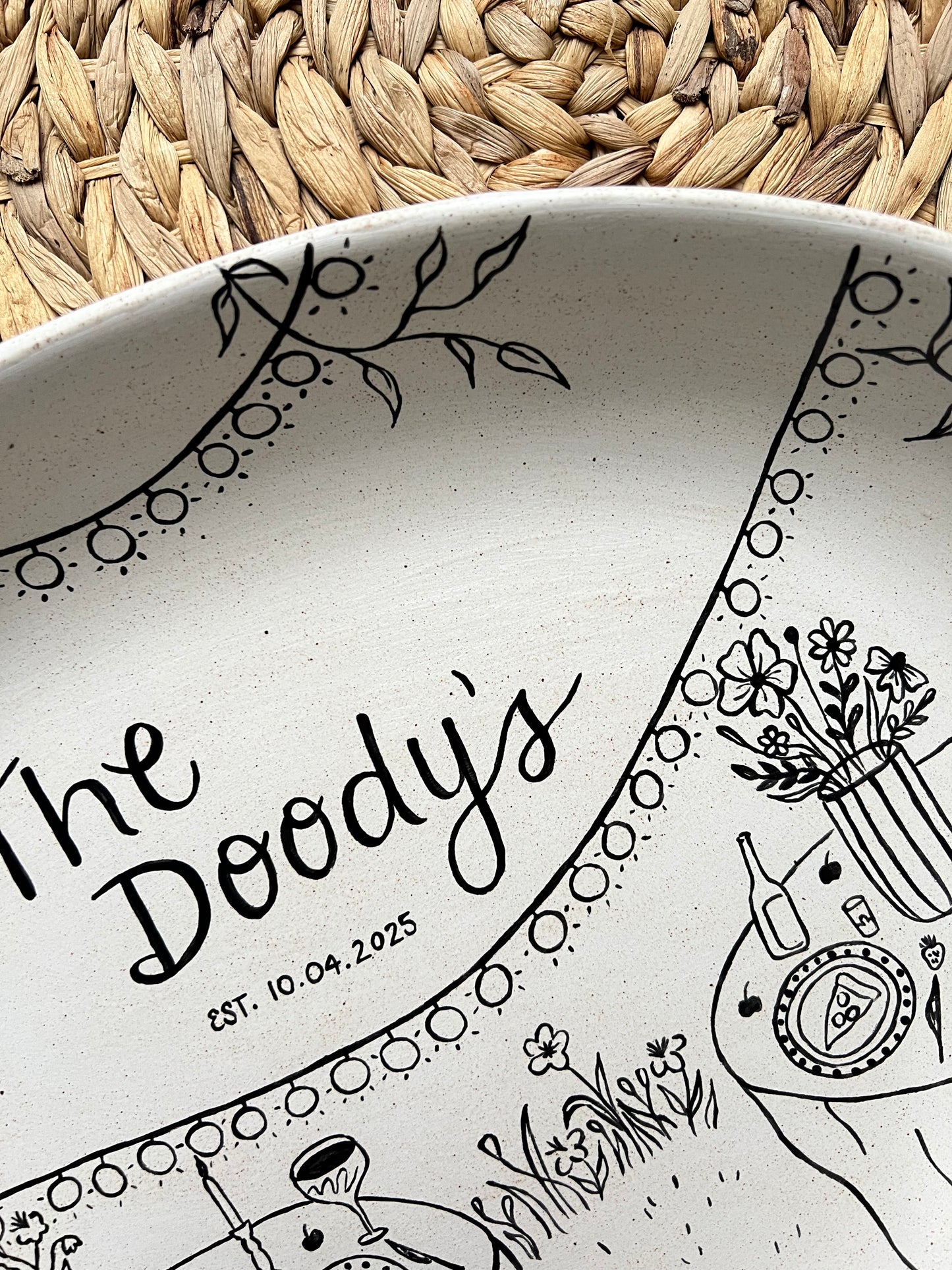 Ceramic tray with black decorative patterns and text on a woven surface