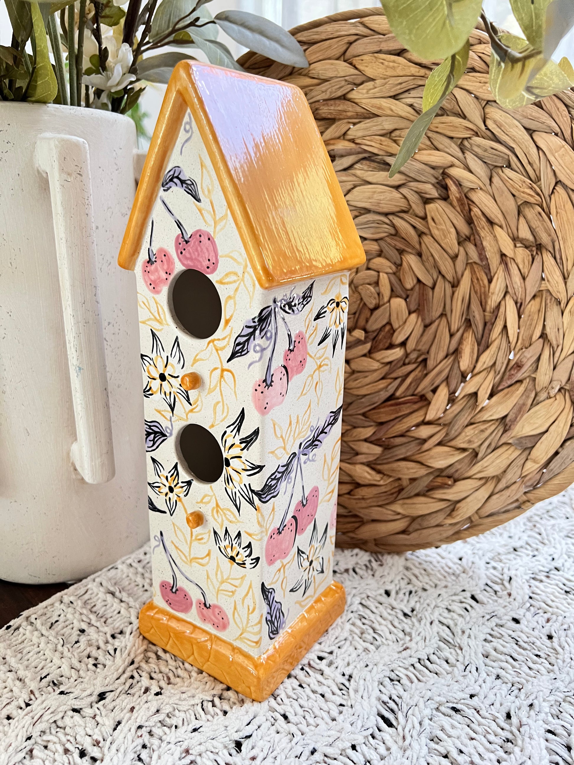 Decorative birdhouse with floral pattern on a textured surface