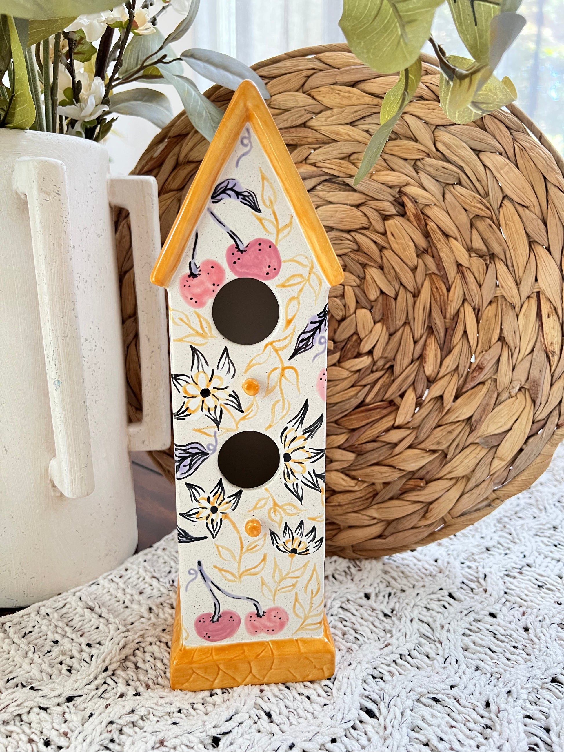 Decorative birdhouse with floral patterns on a textured surface