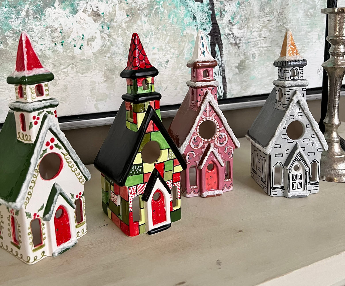 Set of colorful church-shaped candles on a surface with a decorative background.