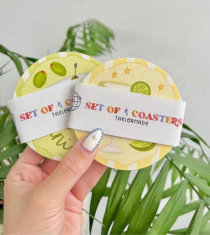 Set of 4 coasters with a decorative label held by a hand against a green plant background