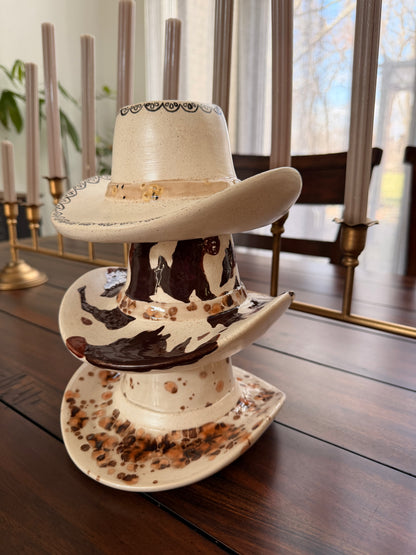 three ceramic cowboy hats stacked on a wooden table with 