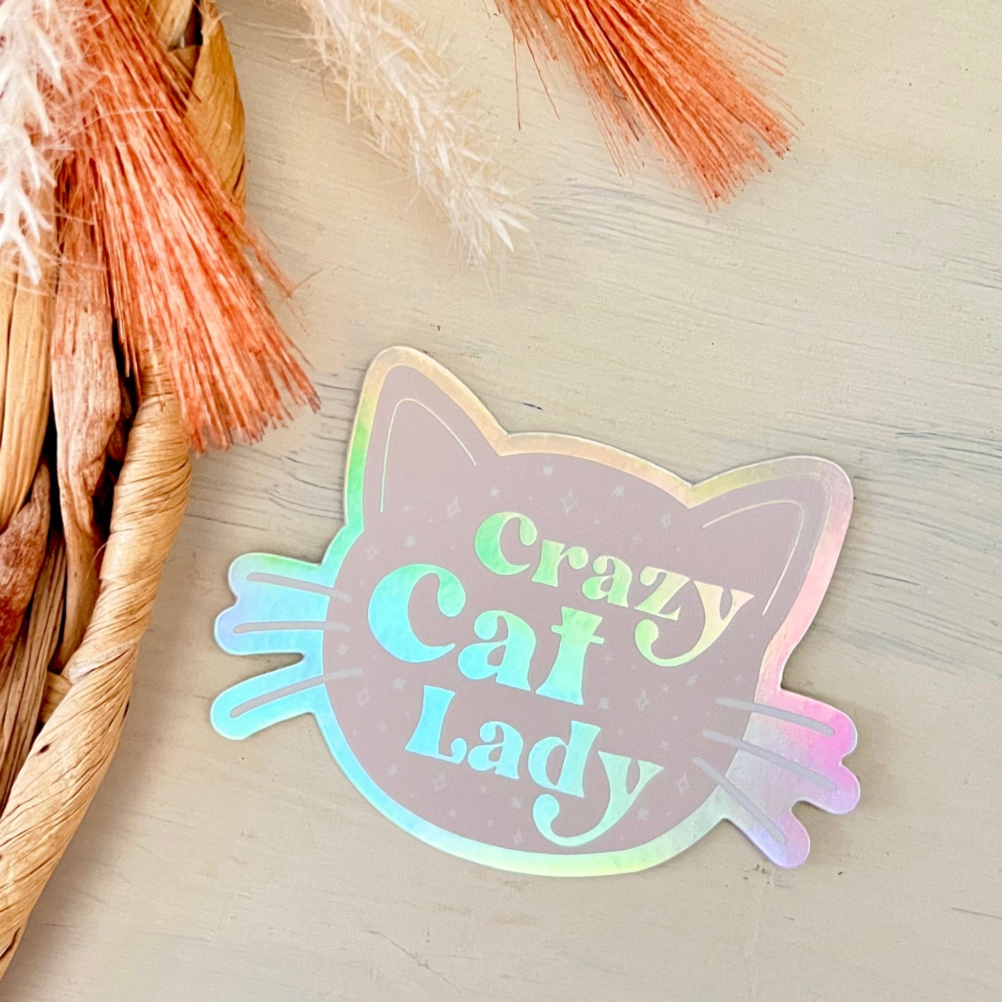 Holographic 'Crazy Cat Lady' sticker on a neutral background with decorative elements.