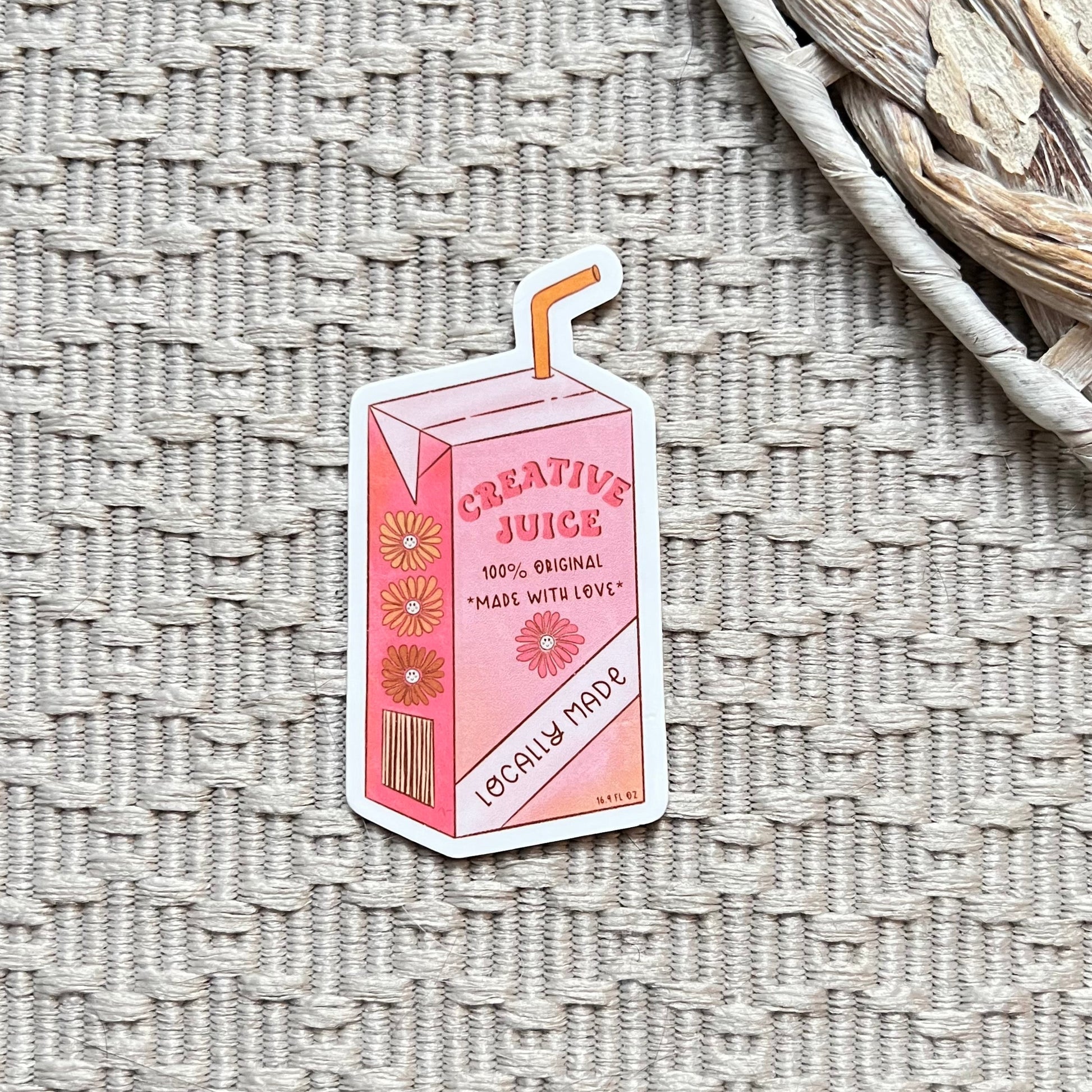 Pink 'Creative Juice' carton with straw sticker on a textured surface
