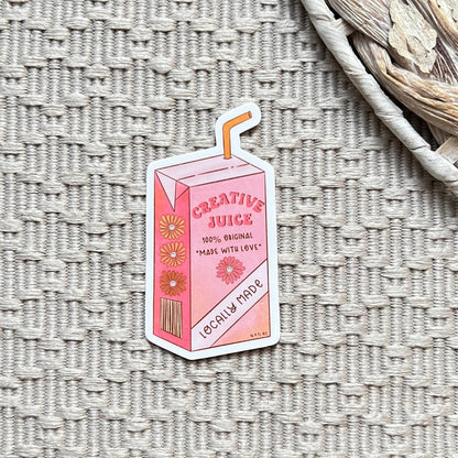 Pink 'Creative Juice' carton with straw sticker on a textured surface
