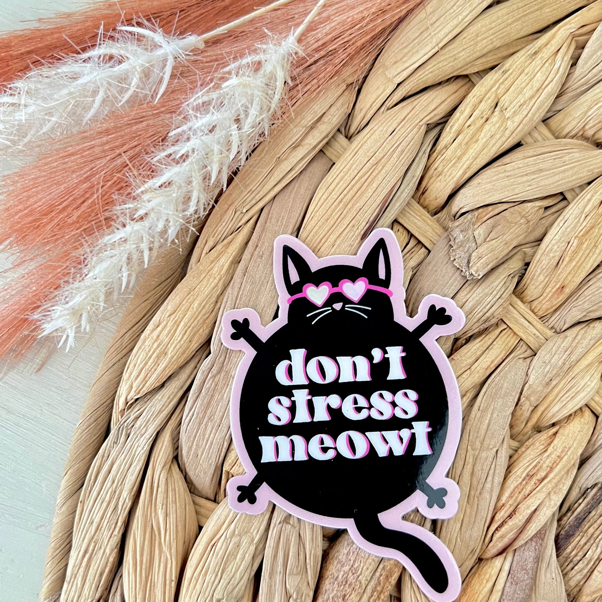 Sticker with a cat design and text 'don't stress meow!' on a woven surface.