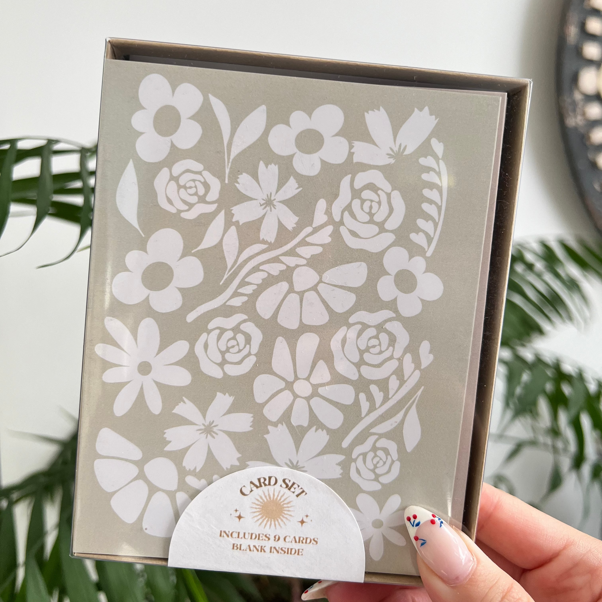 Floral card set with a hand holding it against a light background