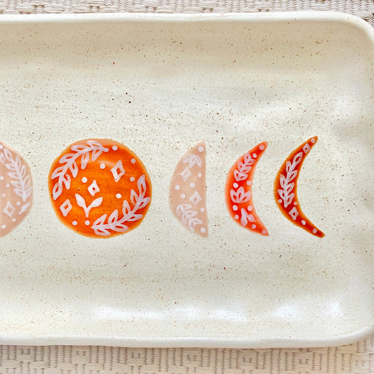 Ceramic tray with decorative moon phases on a textured surface
