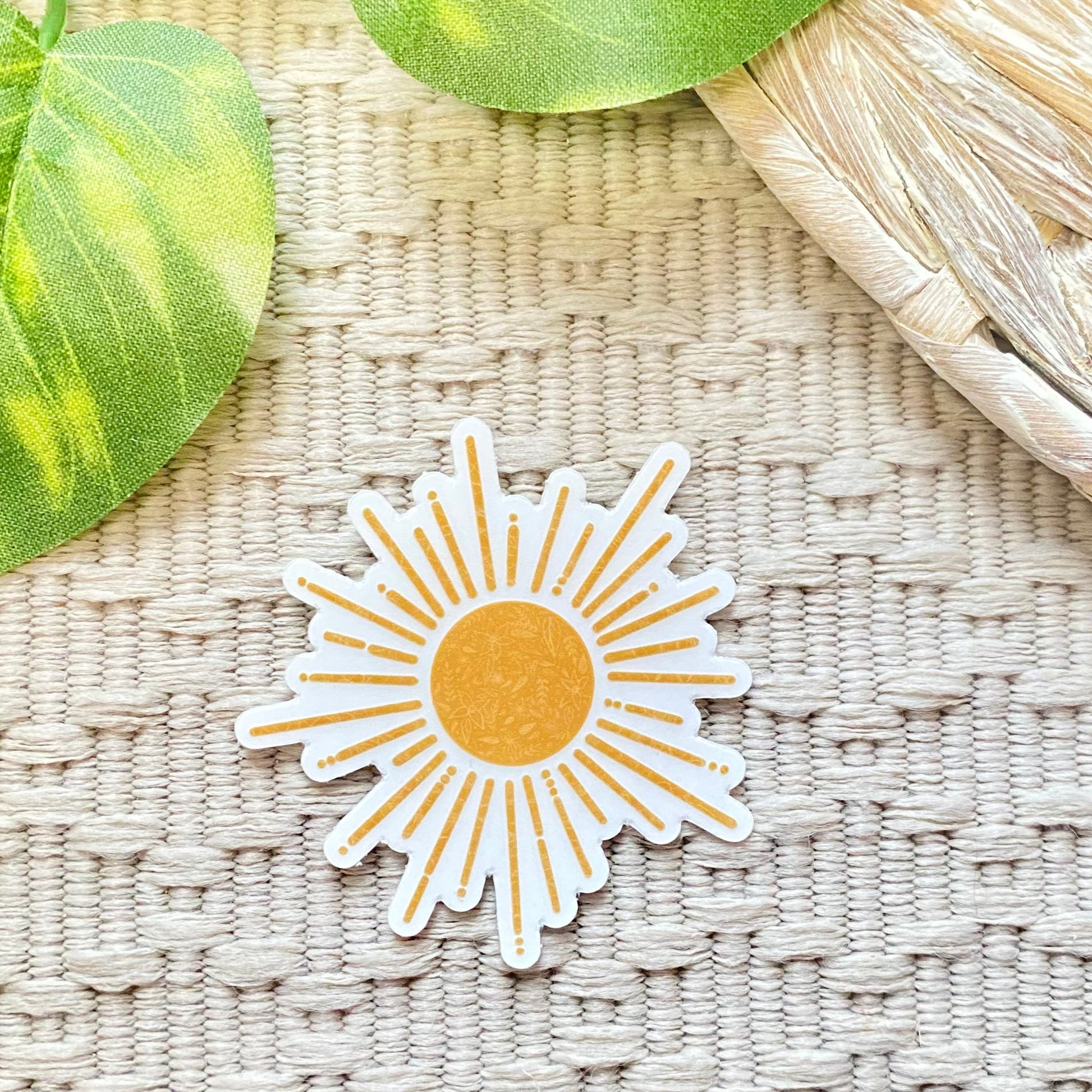 Sun-shaped sticker on a textured surface with leaves