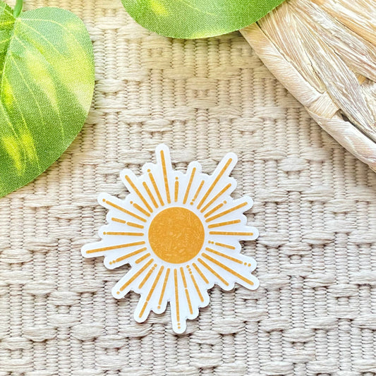 Sun-shaped sticker on a textured surface with leaves