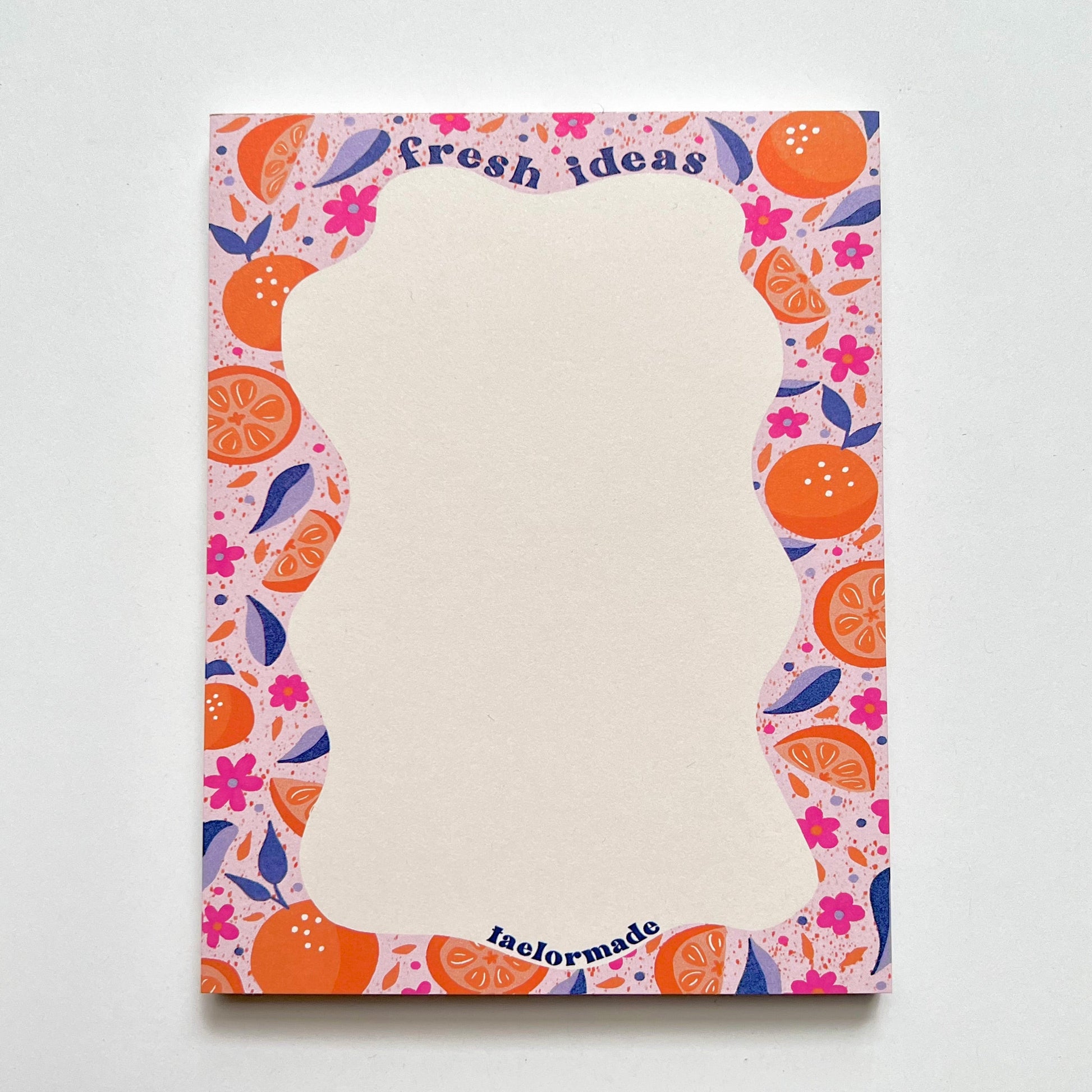 Notepad with colorful fruit and floral pattern on a white background
