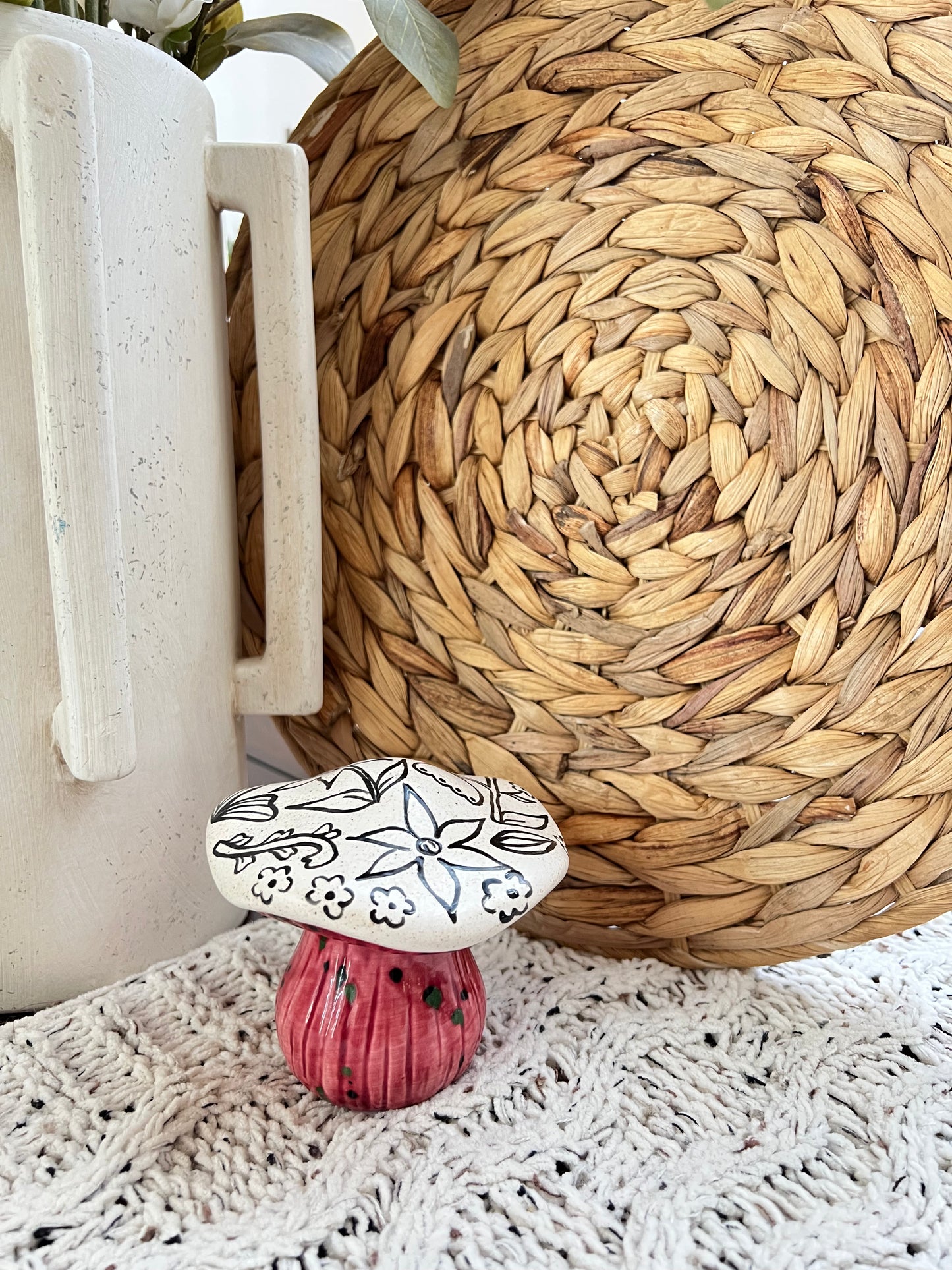 Decorative ceramic mushroom with floral design on a woven mat