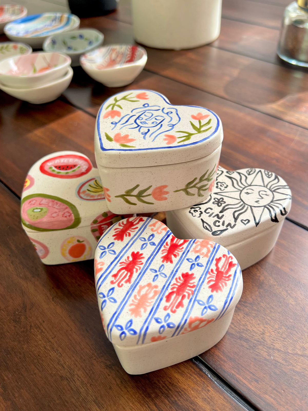 Heart-shaped decorative boxes with various patterns on a wooden surface