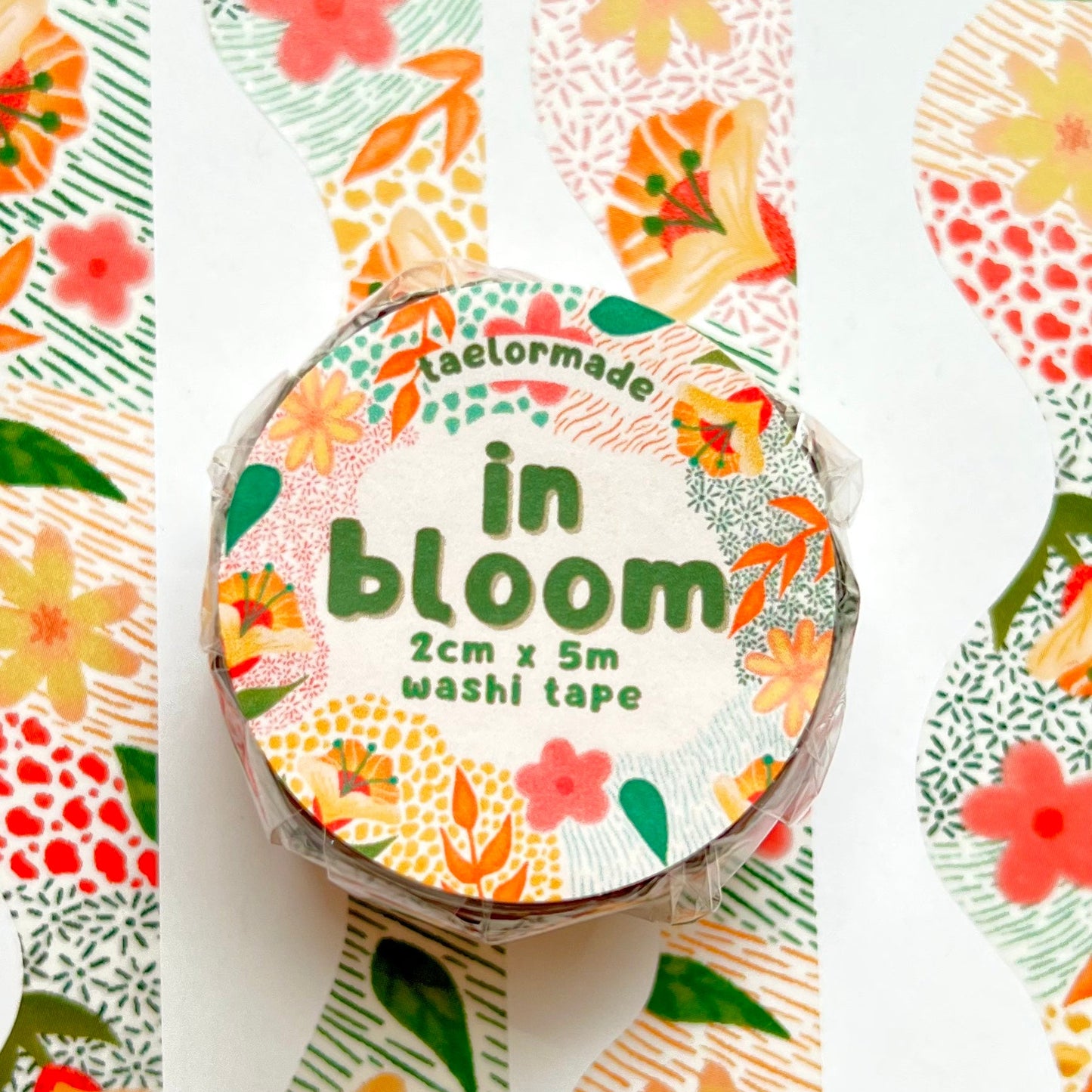 Roll of washi tape with floral design and 'in bloom' text on a white background