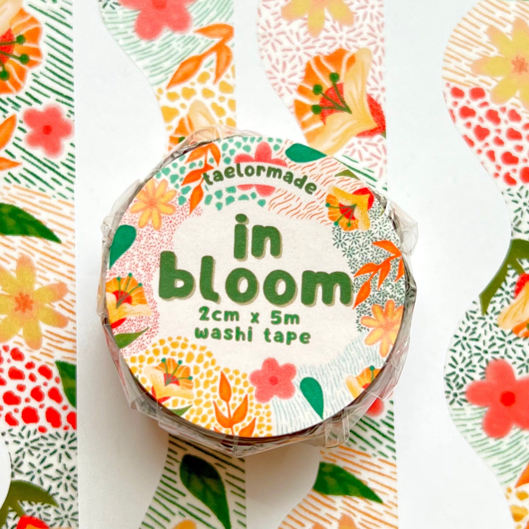 Roll of washi tape with floral design and 'in bloom' text on a white background