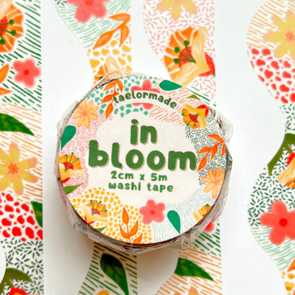 Roll of washi tape with floral design and 'in bloom' text on a white background