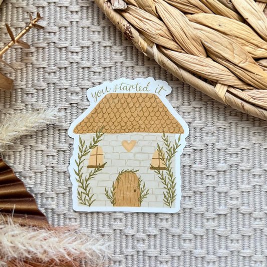 Decorative house-shaped sticker with text on a textured surface