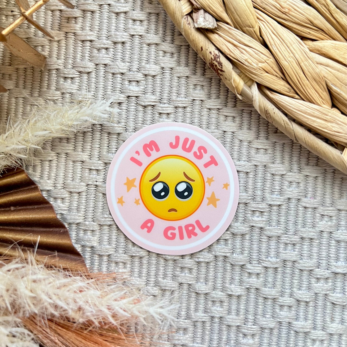 Sticker with emoji and text 'I'm just a girl' on a textured surface