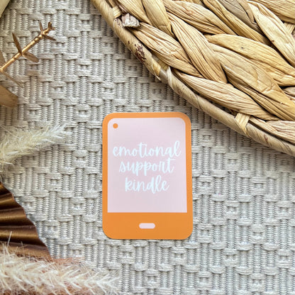 Sticker of a kindle with 'emotional support kindle' text on a textured surface