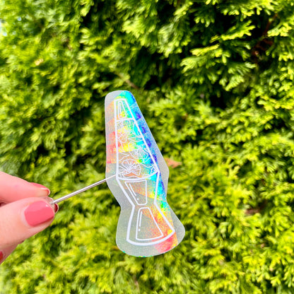 Holographic rainbow making sticker shaped like a lava lamp with flowers inside held in front of green foliage