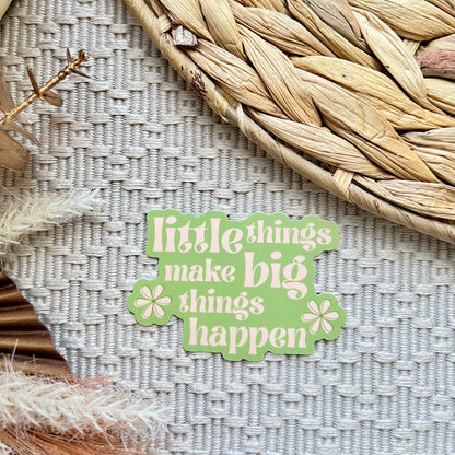 Green sticker with 'little things make big things happen' text on a textured surface