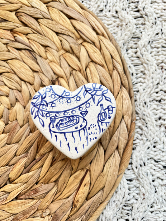 Heart-shaped ceramic box with blue patterns on a woven mat