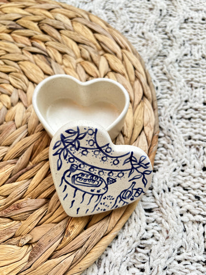 Heart-shaped ceramic object with blue patterns on a woven mat
