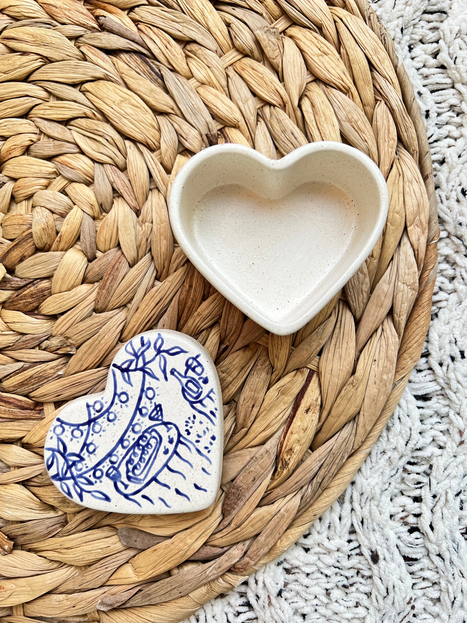 Heart-shaped ceramic box with blue patterns on a woven mat