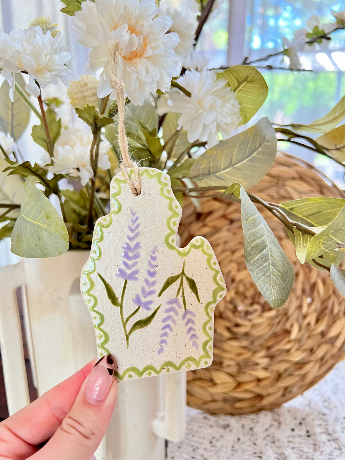 Decorative ornament with floral design held in front of a floral arrangement.