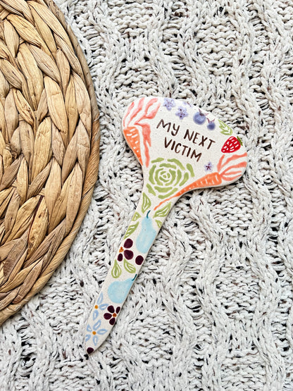 Colorful ceramic garden stake with decorative text on a textured surface