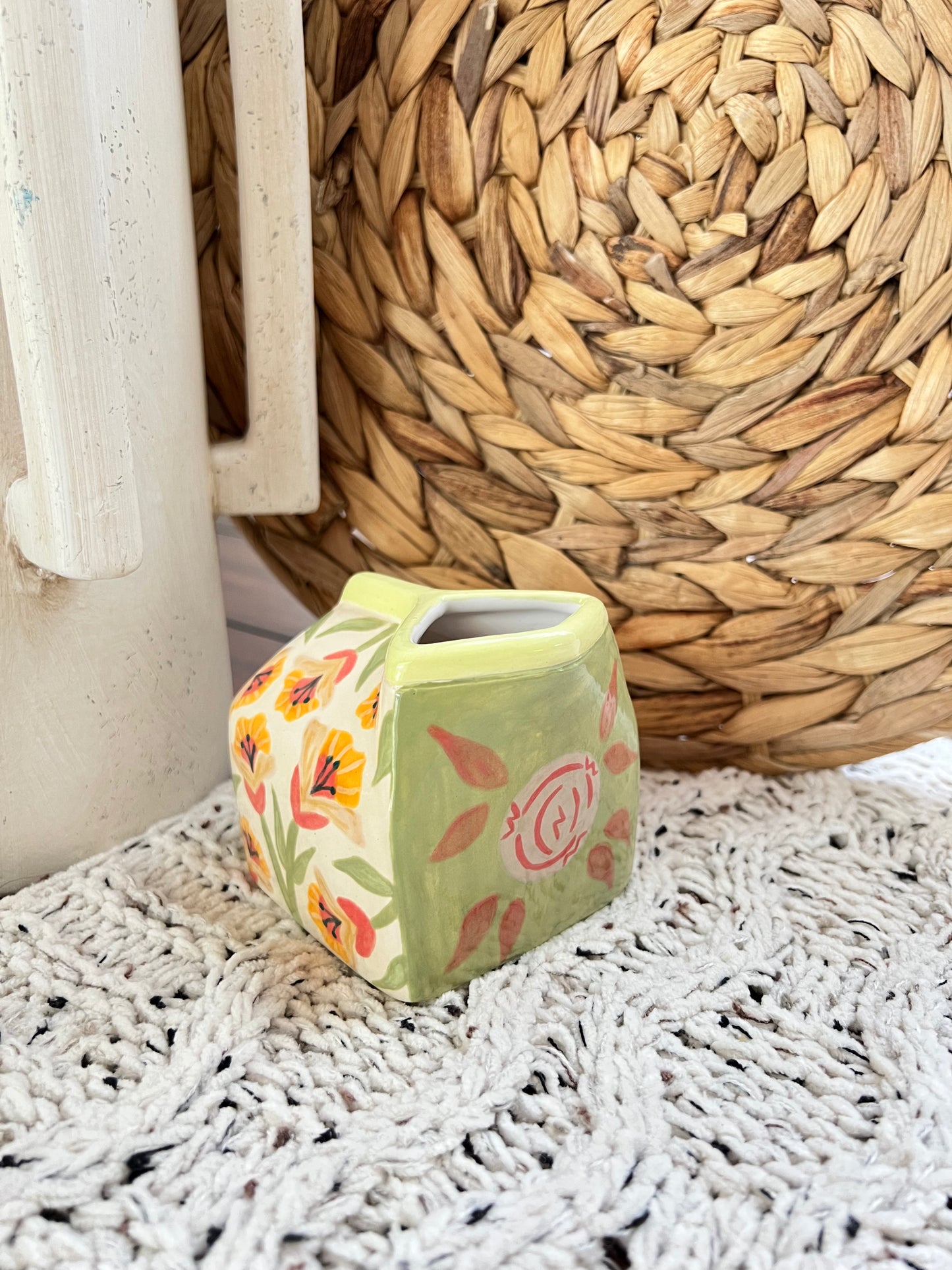 Milk Carton shaped ceramic vase with floral design on a textured surface