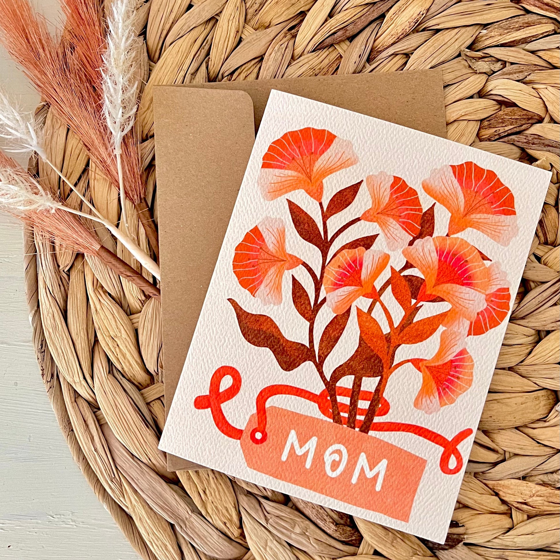 Greeting card with floral design and 'Mom' text on a woven surface