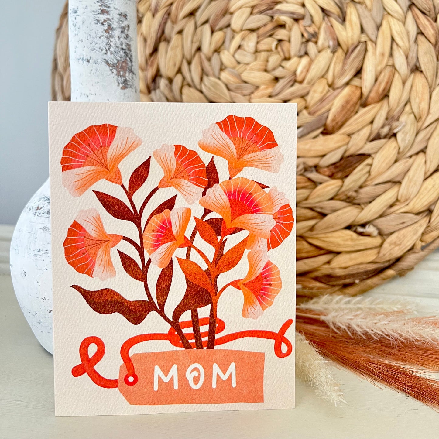 Card with floral design and 'Mom' text on a woven mat background