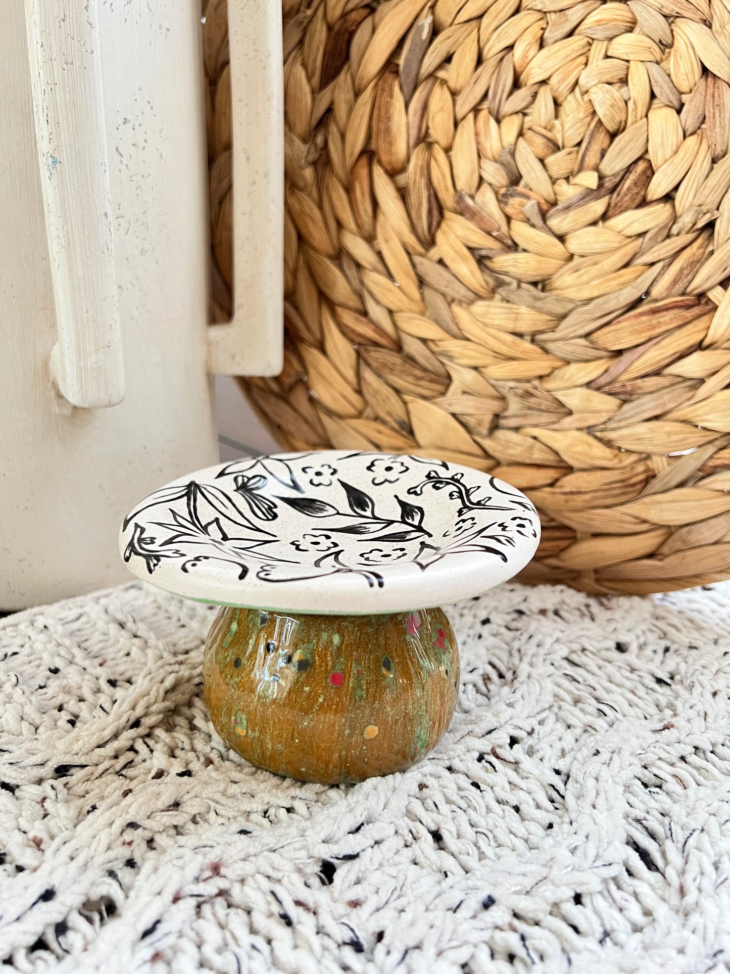 Decorative ceramic mushroom box with black floral design on a textured surface