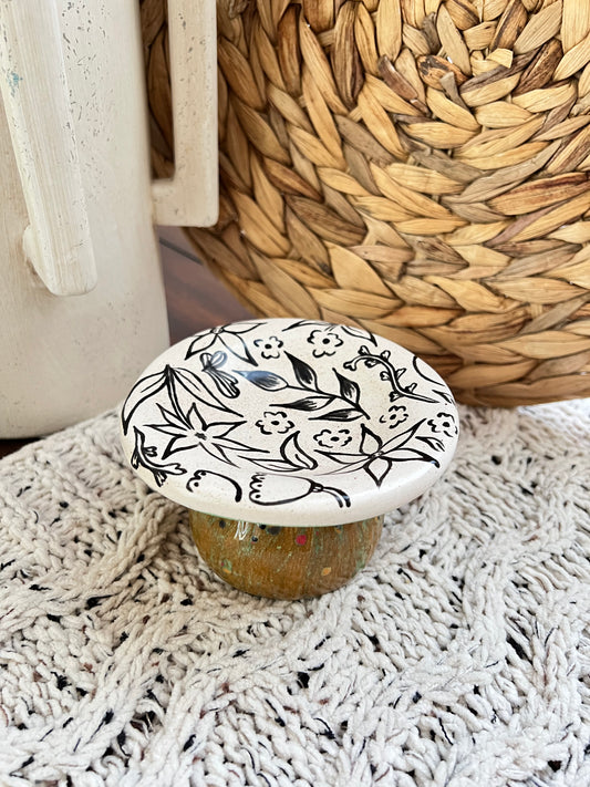 Decorative ceramic mushroom box with floral pattern on a textured surface